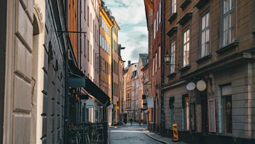 Narrow european street with colorful buildings and cloudy sky